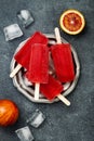 Homemade frozen blood orange natural juice alcoholic popsicles - paletas - ice pops. Overhead, flat lay, top view.