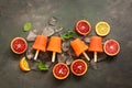 Homemade frozen orange juice popsicles with ice and mint on a dark background. Top view, flat lay, copy space Royalty Free Stock Photo