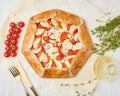 Homemade galette with vegetables, wholegrain pie with tomatoes, zucchini, cheese. Top view, close up. Light white wooden table Royalty Free Stock Photo