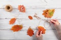 Homemade garland of colored autumn leaves with womans hands