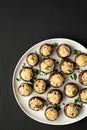 Homemade Garlic Parmesan-Stuffed Mushrooms on a plate on a black background, top view. Copy space Royalty Free Stock Photo