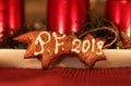 A homemade gingerbread comet covered with white icing and wishing to you PF 2019. In the background christmas candlestick with red Royalty Free Stock Photo