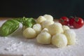 Homemade gnocchi,potato pasta , on floured wood with fresh cherry tomatoes and basil