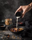 Homemade granola in black bowl. woman hand pour milk