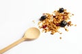 Homemade granola or granola with dried berries and nuts sprinkled on a white plate next to a wooden spoon. Home-made food, healthy