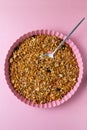 Homemade granola with nuts and seeds on baking sheet on pink background. Granola for healthy breakfast.