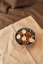Homemade granola in a plate with nuts, honey, blueberries, banana and other natural ingredients served on napkin over