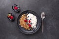 Homemade granola with yogurt and fresh berries in black ceramic plate on dark stone background. Healthy vegan breakfast Royalty Free Stock Photo
