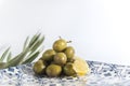 Homemade green olives in a chinese plate  with olive tree branches and a piece of lemon on a white background, isolated Royalty Free Stock Photo