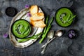 Homemade green spring asparagus cream soup decorated with black sesame seeds and edible chives flowers. Royalty Free Stock Photo