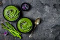 Homemade green spring asparagus cream soup decorated with black sesame seeds and edible chives flowers.