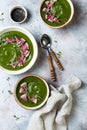 Homemade green spring spinach cream soup decorated with watermelon radish, black sesame seeds and microgreens.