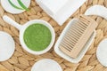 Homemade green tea (kelp, algae, spirulina) face or hair mask in a small bowl and wooden hairbrush.