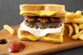 Homemade Grilled Cheese Burger with French Fries on a rustic wooden board on a black background, side view. Close-up Royalty Free Stock Photo