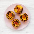 Homemade grilled peaches on a pink plate on a white wooden surface, top view. Flat lay, overhead, from above. Close-up Royalty Free Stock Photo