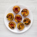 Homemade grilled peaches on a white plate on a white wooden table, view from above. Flat lay, top view, overhead. Close-up Royalty Free Stock Photo