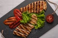Grilled turkey breast sliced steaks with baked peppers, lettuce and tomato on a black board. Top view, close-up Royalty Free Stock Photo