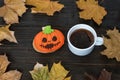 Homemade Halloween cookies pumpkin and Cup of coffee on wooden table with autumn leaves Royalty Free Stock Photo