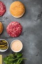 Homemade hamburger. Raw beef patties, sesame buns with other ingredients, on gray stone background, top view flat lay, with copy Royalty Free Stock Photo