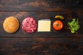 Homemade hamburger. Raw beef patties, sesame buns with other ingredients, on old dark  wooden table background, top view flat lay Royalty Free Stock Photo