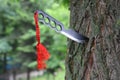 Homemade, handmade, fist knife, black with a red ribbon sticking out of a tree trunk