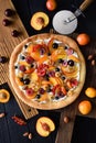 Homemade healthy dessert. Fruit pizza with raw peaches, apricots, cherries, currants and raspberries with ricotta frosting on dark