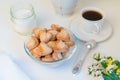 homemade heart shaped sesame shortbread cookies in a glass bowl, a cup of black coffee, sugar and wildflowers on a white table Royalty Free Stock Photo