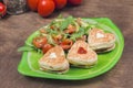 Homemade heart shaped toasts sandwiches with ham and cheese with fresh vegetable salad and arugula on a plate Royalty Free Stock Photo