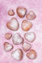 Homemade heart sheped donuts with powdered sugar on pnk background. Royalty Free Stock Photo