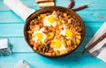 Hearty Breakfast Skillet with Eggs Potatoes and minced meat on blue wooden table Royalty Free Stock Photo