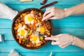 Homemade Hearty Breakfast Skillet with Eggs Potatoes and minced meat on blue wooden table Royalty Free Stock Photo