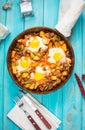 Homemade Hearty Breakfast Skillet with Eggs Potatoes and minced meat on blue wooden table Royalty Free Stock Photo