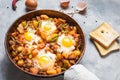 Homemade Hearty Breakfast Skillet with Eggs Potatoes and minced meat on concrete table