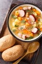 Homemade hearty pea soup with vegetables, bacon and sausages close-up in a bowl. Vertical top view Royalty Free Stock Photo