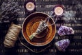 Homemade herbal lavender lavendula smudge stick smoldering on brown plate with candles.