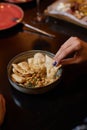 Homemade hummus decorated with chickpeas, parsley, garlic and olive oil. Female hand dipping pita bread triangles in Royalty Free Stock Photo