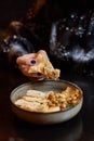 Homemade hummus decorated with chickpeas, parsley, garlic and olive oil. Female hand dipping pita bread triangles in Royalty Free Stock Photo