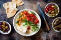 Homemade hummus with roasted cherry tomatoes, olives, dolma and pita bread.