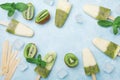 Homemade ice cream or popsicles from kiwi smoothie and yogurt decorated with mint and ice. Top view.