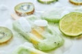 Melting green ice cream on a stick with pieces of peach on a gray background with pieces of ice, kiwi, lime and kiwi Royalty Free Stock Photo