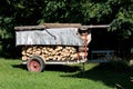 Homemade improvised tractor trailer made of strong metal stacked with prepared firewood and covered with tarpaulin for protection