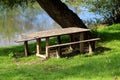 Homemade improvised wooden table with two benches made of narrow wooden boards and wooden logs at local river bank