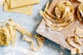 Homemade italian pasta, ravioli, fettuccine, tagliatelle on a wooden board and on a blue background. The cooking process