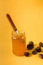 Homemade jam in a glass jar and chestnuts on yellow background