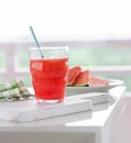 Homemade juicy cold drink with watermelon and water in a glass with blue straw on a wooden cut board