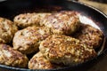 Homemade juicy minced meat patties burgers in iron cast frying pan, weathered wood kitchen table