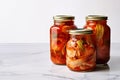 Homemade Korean fermented cabbage Kimchi preserved in glass jars, on marble kitchen countertop. Generative AI