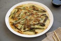 Homemade korean Pajeon scallion pancake on a white plate on a gray surface, side view. Asian food. Close-up Royalty Free Stock Photo