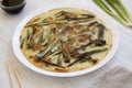 Homemade korean Pajeon scallion pancake on a white plate on a white wooden background, side view. Asian food. Close-up Royalty Free Stock Photo