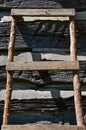 A homemade ladder leans against a log cabin wall Royalty Free Stock Photo